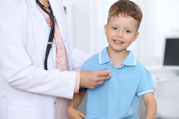 Foto médico y paciente en el hospital niño feliz divirtiéndose mientras lo examinan con estetoscopio concepto de atención médica y seguro