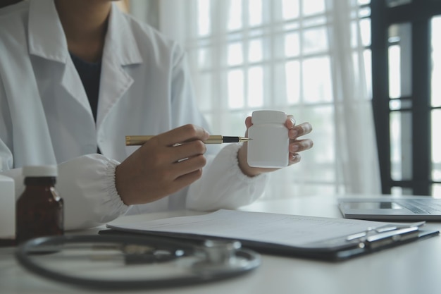 Médico y paciente sentados y hablando en un examen médico en el consultorio del hospital. Terapeuta llenando registros del historial de medicación. Concepto de medicina y atención sanitaria.