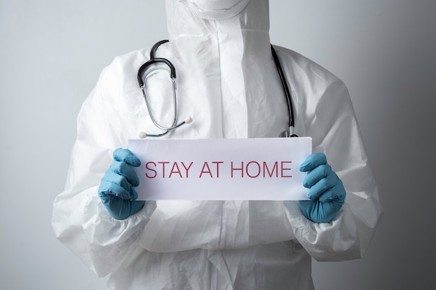 Un médico con un papel con quedarse en casa sosteniendo en la mano, proteger contra el coronavirus o la epidemia de Covid-19