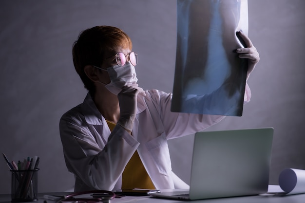 El médico parece preocupado al inspeccionar la película de rayos X de los pulmones durante la crisis del brote pandémico COVID-19