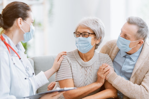 Médico y pareja de ancianos con mascarillas durante el brote de coronavirus y gripe