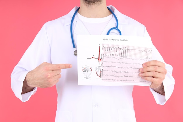 Médico - pasante con cardiograma sobre fondo rosa