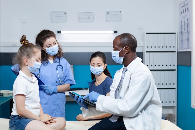 Médico pediatra afroamericano con mascarilla protectora contra el covid