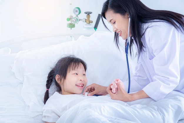 Médico pediatra en bata blanca uniforme escuchar el sonido de los pulmones del paciente niña con estetoscopio.