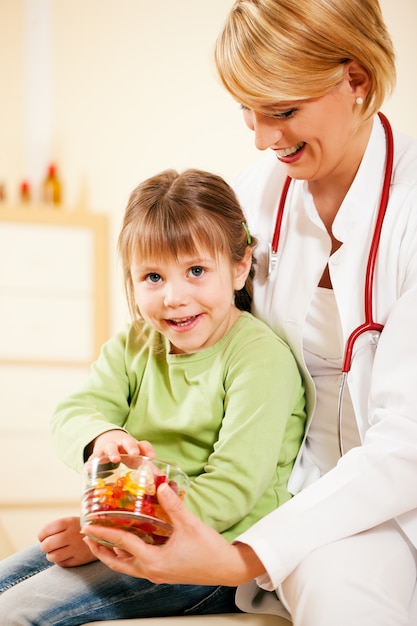 Médico pediatra dando dulces al pequeño paciente