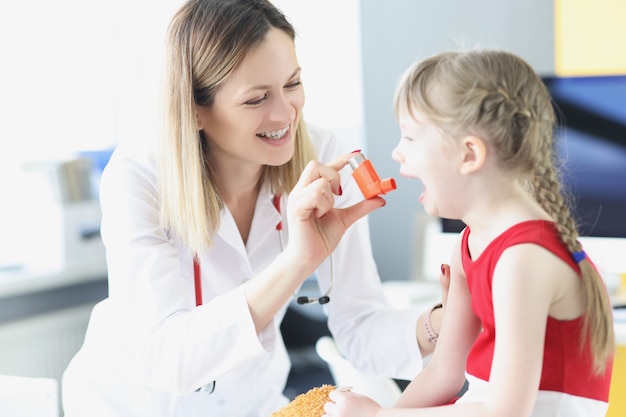 Médico pediatra enseñando a la niña a usar el inhalador hormonal en el tratamiento clínico de