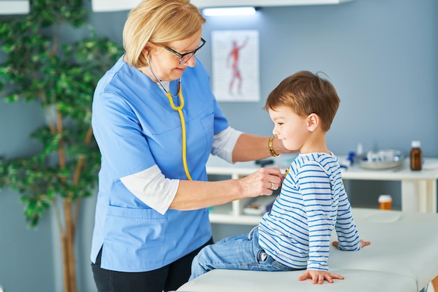Médico pediatra examinando crianças na clínica. Foto de alta qualidade