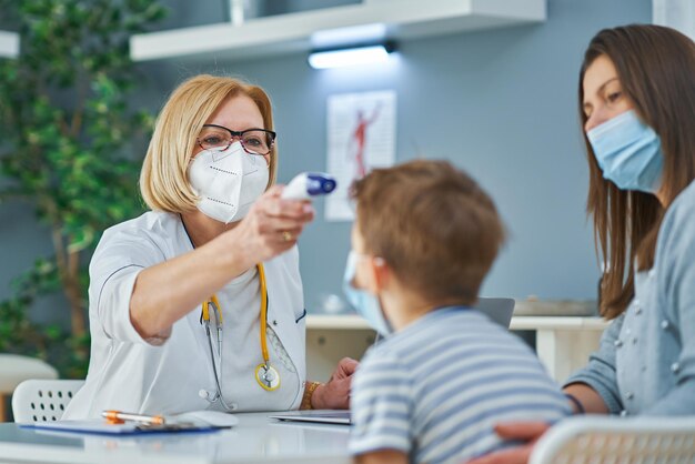 Médico pediatra examinando crianças na verificação de temperatura clínica. Foto de alta qualidade