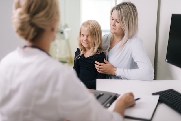 Médico pediatra examinando garota linda de cabelo loiro