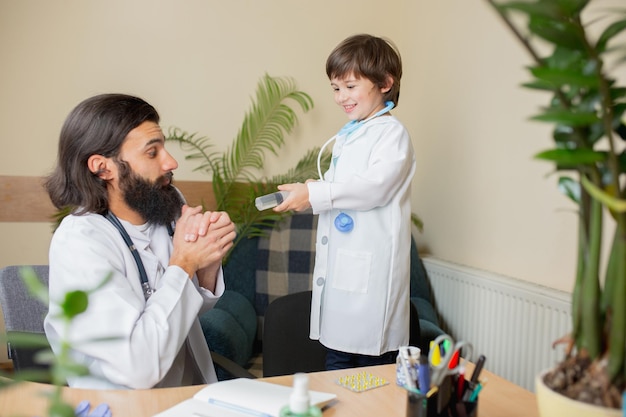 Médico pediatra examinando a un niño en el consultorio médico comfortabe