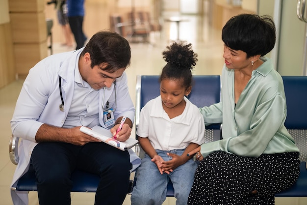 Médico pediatra que examina a una niña con su madre