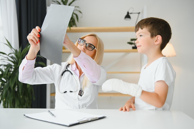 Médico pediatra vendando el brazo del niño Brazo roto en un niño