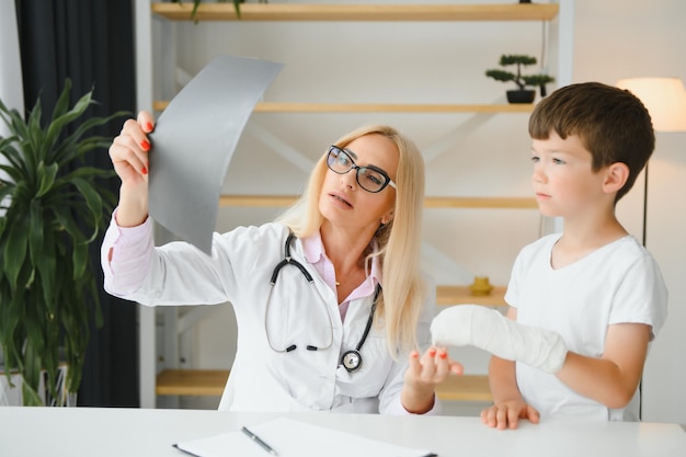 Médico pediatra vendando el brazo del niño Brazo roto en un niño