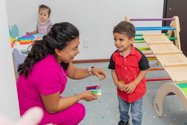 Médico pediátrico riéndose con un niño en el área de juegos de su consultorio médico