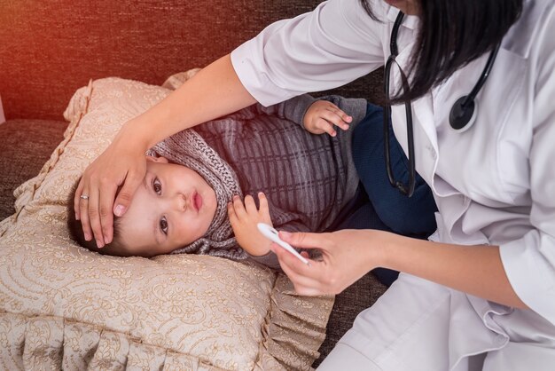 Médico con un pequeño paciente que tiene fiebre.