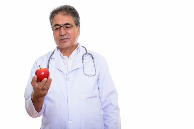 Médico persa senior sosteniendo y mirando manzana roja