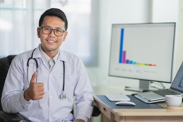 Médico polegares para cima sorrindo e trabalhando com computador portátil médico masculino trabalha no hospital de escritório conceito de hospital de saúde