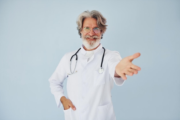 Médico positivo profissional Homem moderno elegante sênior com cabelos grisalhos e barba dentro de casa
