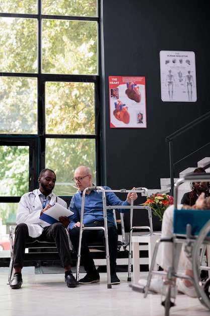 Foto médico praticante segurando prancheta com resultados de diagnóstico de doença explicando perícia médica para paciente sênior com quadro wallking durante visita de check-up na área de espera do hospital. serviço de medicina