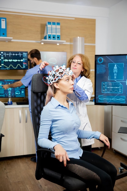 Médico preparando as ondas cerebrais, escaneando o fone de ouvido para testes em uma paciente do sexo feminino. Experimento clínico