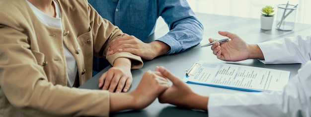 Foto médico prestando consulta de saúde compassiva enquanto jovem casal paciente de mãos dadas conforta um ao outro após relatório de infértil consultoria de fertilidade médica e reprodutiva neoteric