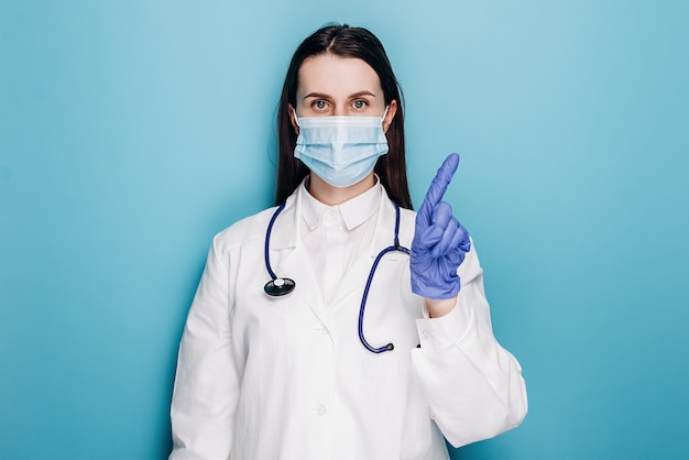 Médico profesional en mascarilla protectora y guantes advirtiendo a la gente