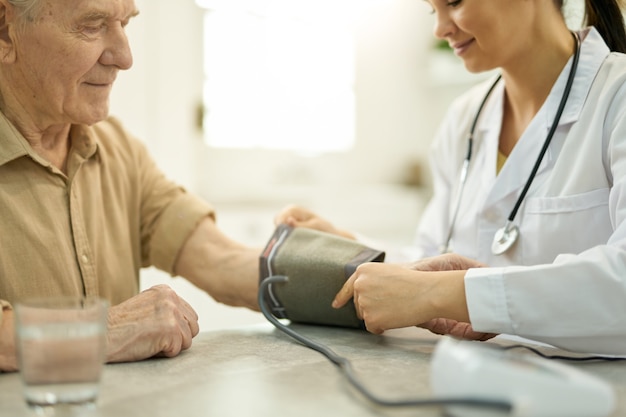 Foto médico profesional preparándose para controlar la presión arterial del hombre mayor