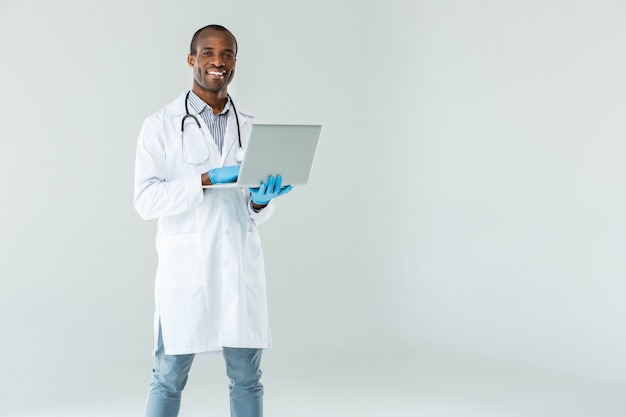 Médico profissional alegre sorrindo enquanto usa seu laptop