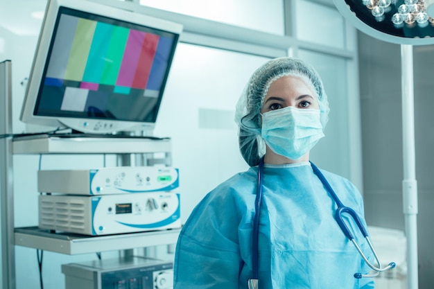 Médico profissional usando máscara e uniforme na sala de cirurgia. Equipamento moderno atrás dela