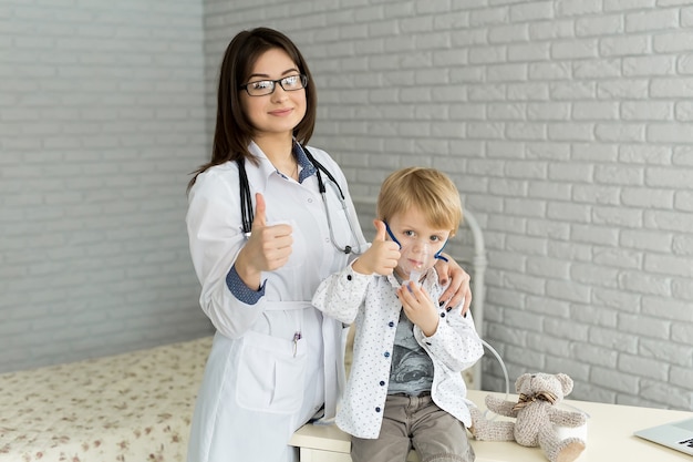 Médico que aplica el tratamiento de inhalación de medicamentos en un niño con terapia de inhalación para el asma por la máscara del inhalador.