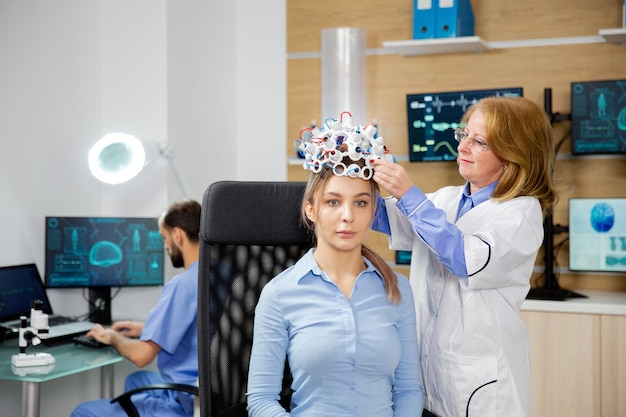 Médico que arregla las ondas cerebrales que escanean los auriculares para un paciente. Laboratorio de neurología y dispositivo de escaneo.