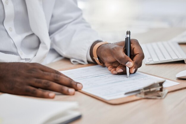 Médico que escribe una receta o un historial médico o un seguro en su oficina y trabaja en un documento de salud Primer plano de un profesional de la salud negro o médico de cabecera que firma un contrato