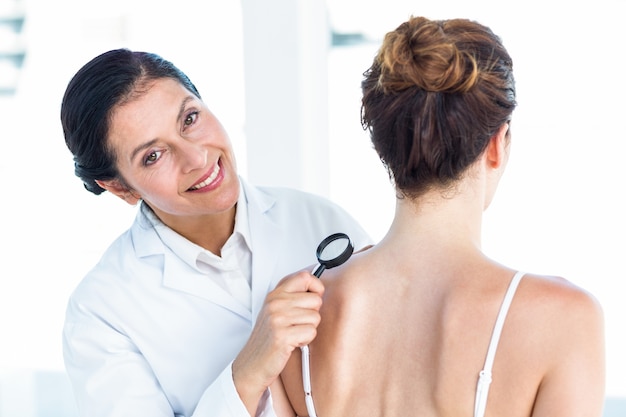 Foto médico que examina paciente com lupa