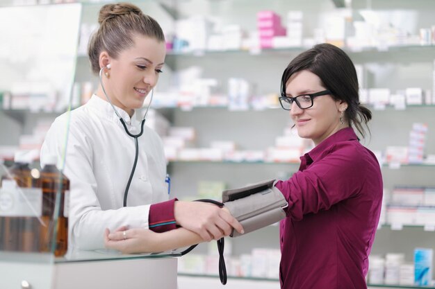 médico que mide la presión arterial y el ritmo cardíaco en un hospital o en una farmacia con una paciente joven