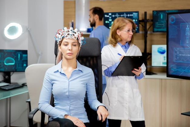 Médico que monitorea la evolución del paciente durante la prueba de auriculares de neurología y anota en el portapapeles. Experimento y estudio médico