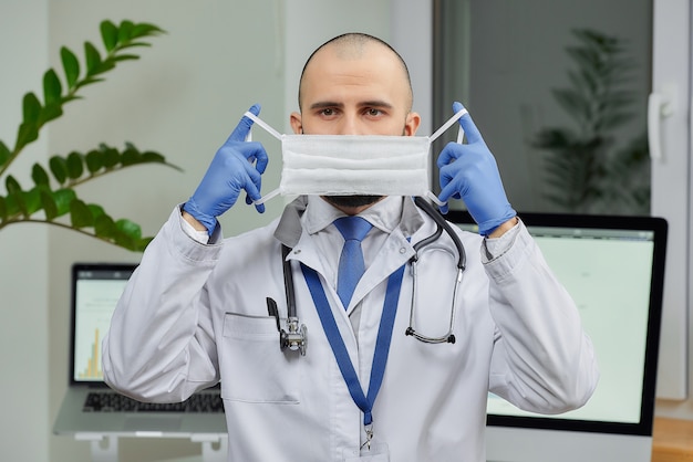 Un médico que se pone una mascarilla protectora para evitar la propagación del coronavirus (COVID-19) en su consultorio.