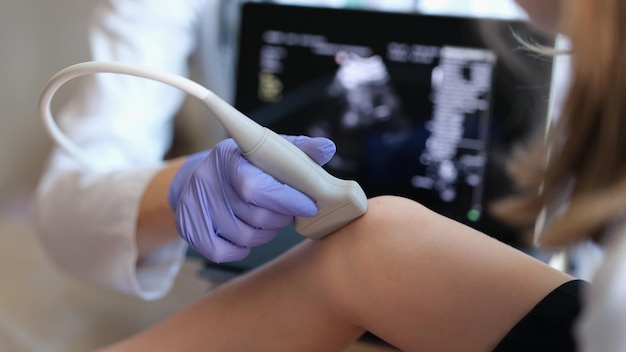 Médico que realiza un examen de ultrasonido de la articulación de la rodilla en el diagnóstico de primer plano del niño del hueso
