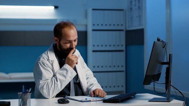 Médico que tiene una discusión remota con el equipo que discute la experiencia médica durante la conferencia de reunión de videollamada. Médico que trabaja tarde en la noche en la oficina del hospital planificando el tratamiento de atención médica