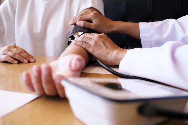 Foto médico que verifica a pressão sanguínea arterial do paciente