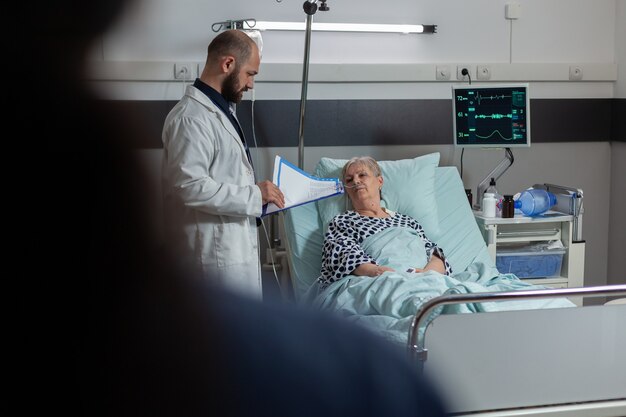 Médico questionando mulher idosa deitada em uma cama de hospital