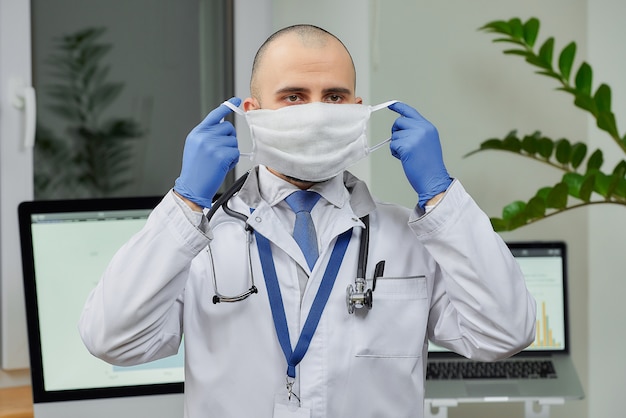 Un médico quitándose una mascarilla protectora en su oficina.