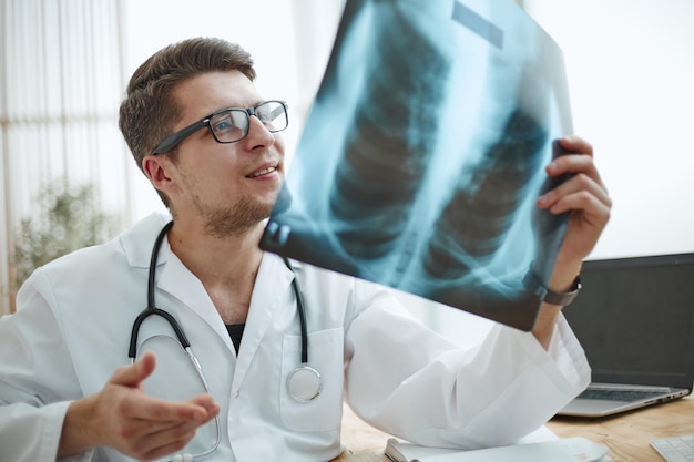 Médico radiologista masculino examina raios-x em um consultório médico