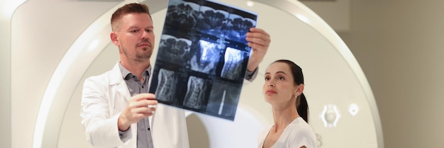 Médico radiólogo mirando la instantánea de la columna del paciente frente a la hernia espinal de la máquina de resonancia magnética