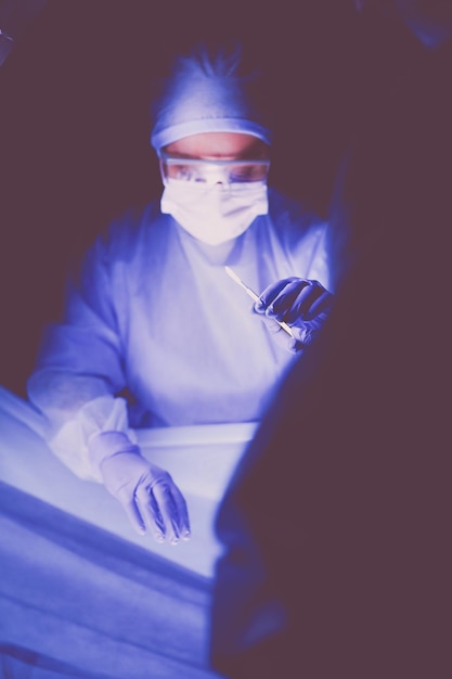 Médico realizando cirurgia em um fundo escuro
