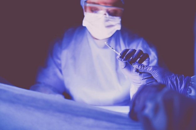 Foto médico realizando cirurgia em um fundo escuro