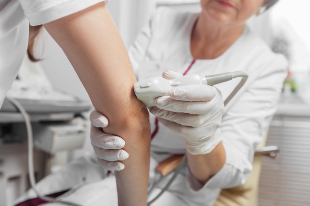 Foto médico realizando exame de ultrassom do cotovelo de pacientes na clínica