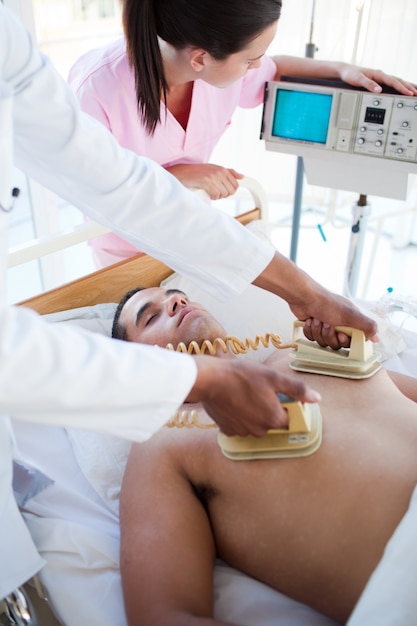 Foto un médico reanimando a un paciente con un desfibrilador