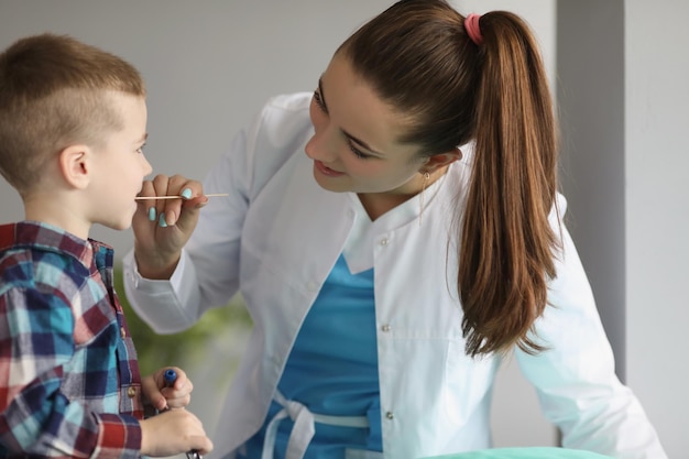 Médico recolecta material biológico de una prueba de hisopado de coronavirus de saliva de niño para niños