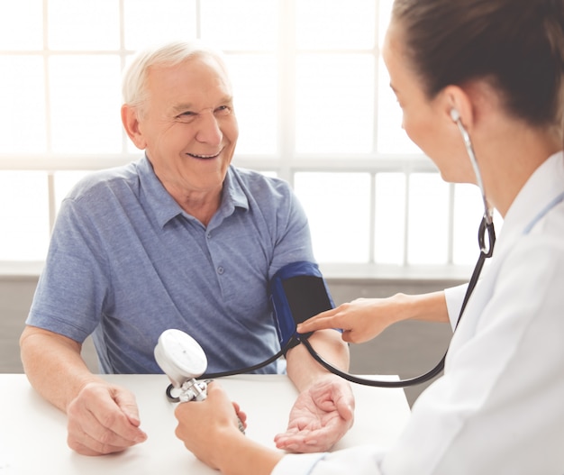 El médico revisa el pulso de un paciente viejo en la clínica.