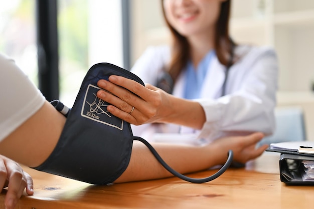 Un médico revisando el pulso y la presión arterial del paciente con un monitor en la sala de examen